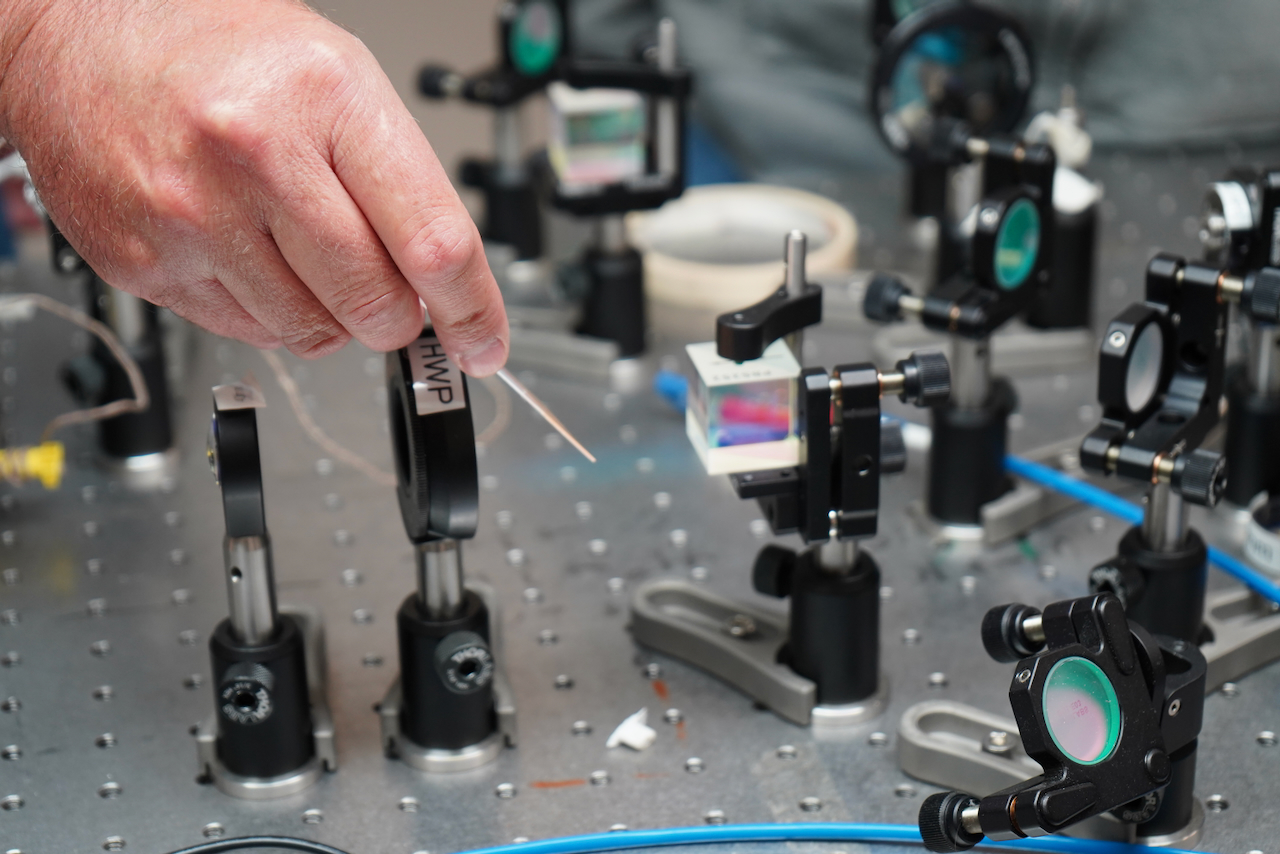 A researcher adjusts optical equipment on a lab table.