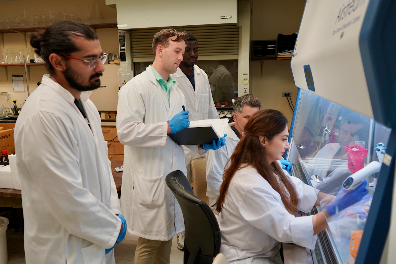 Photograph of scientists in white lab coats working together in a laboratory.