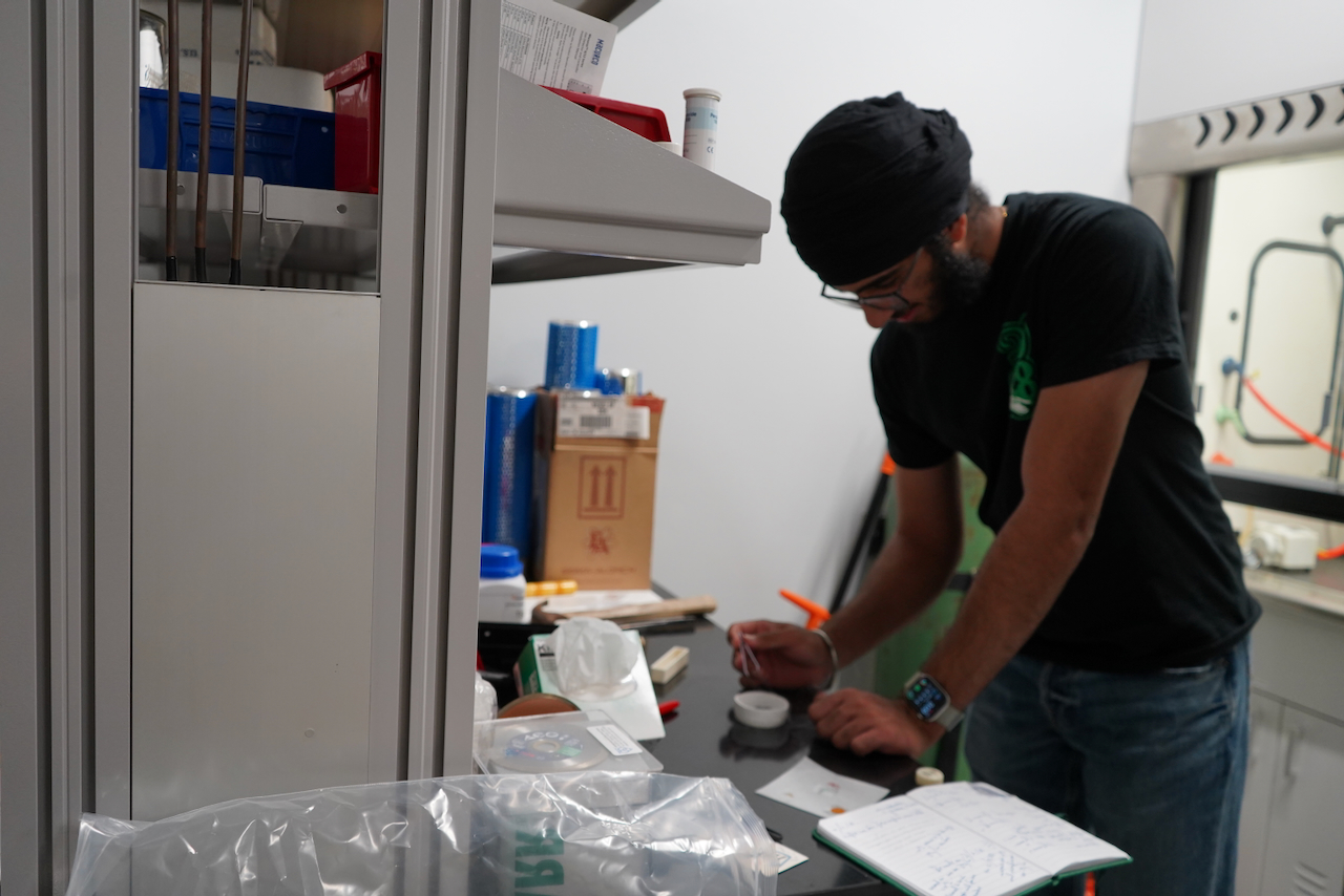 Man in a black shirt writing something on a metal lab table