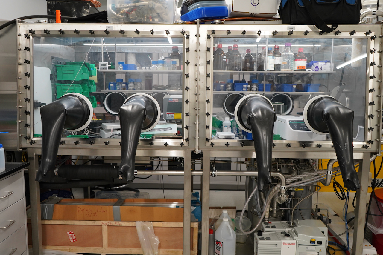 Photograph of a double-chamber glove box containing chemicals and equipment.