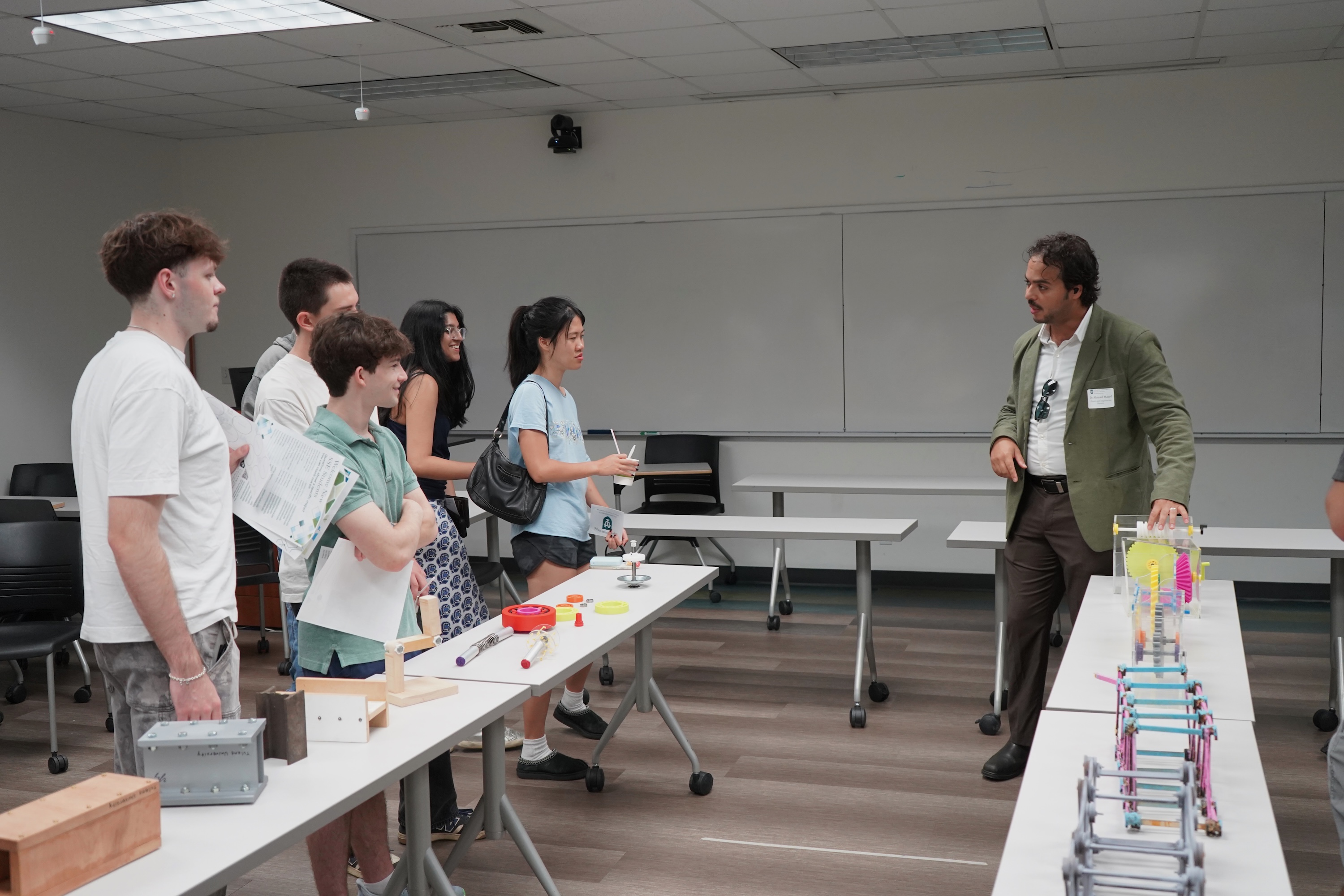 Photograph of a teacher and students standing around tables in a classroom.