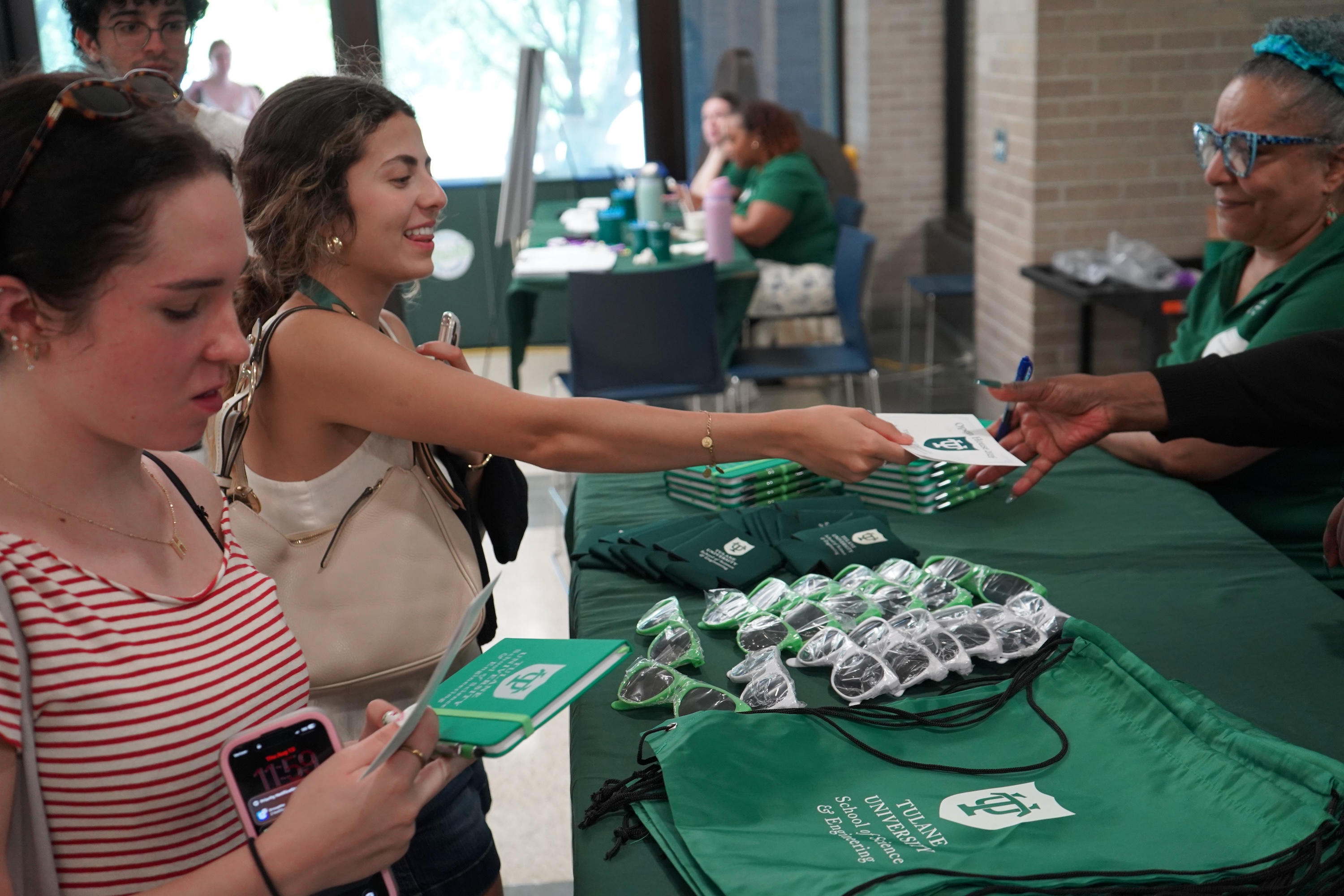Photograph of young women collecting items at a table with promotional materials.