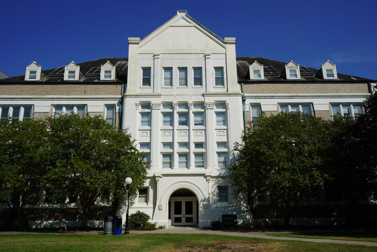 Photograph of a large, multi-story white building with a pitched roof and a central arched entrance.