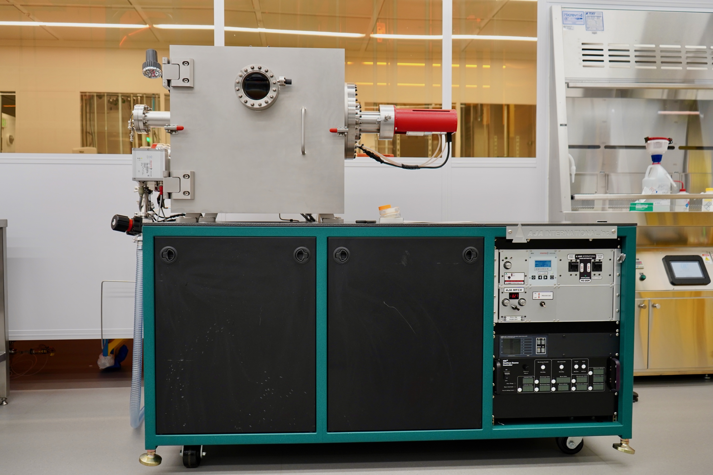 Photograph of a stainless steel vacuum chamber apparatus on a teal and black lab cart.