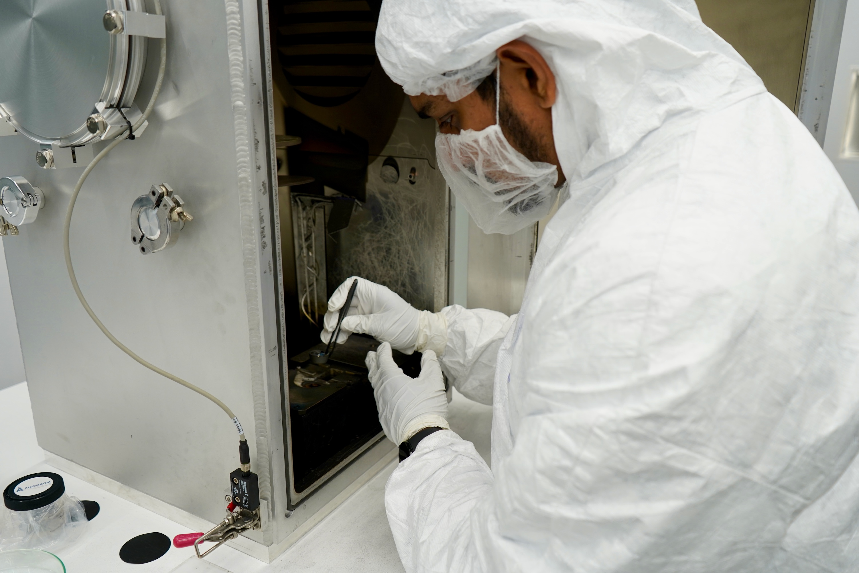 Photograph of a technician in protective gear working with scientific equipment.