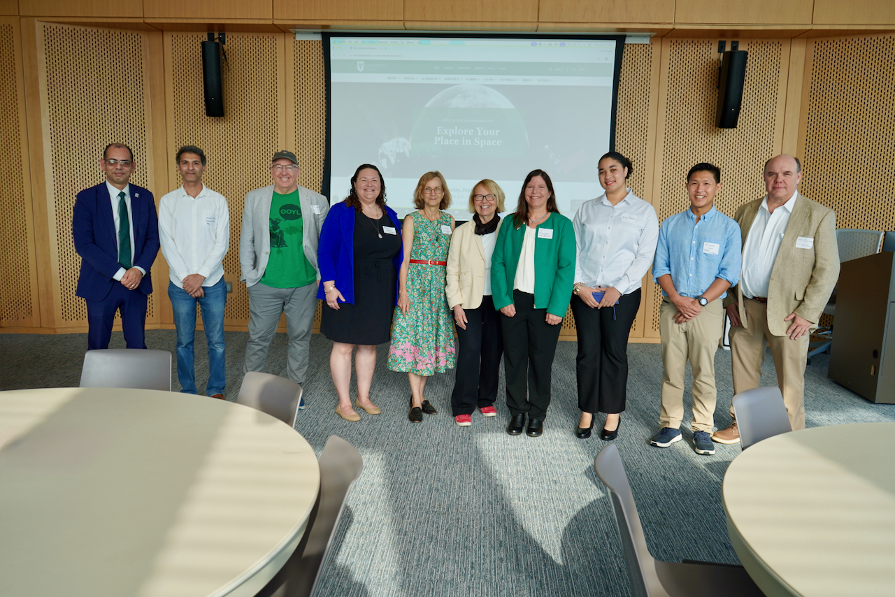 A photograph of a diverse group of nine people standing in a conference room.