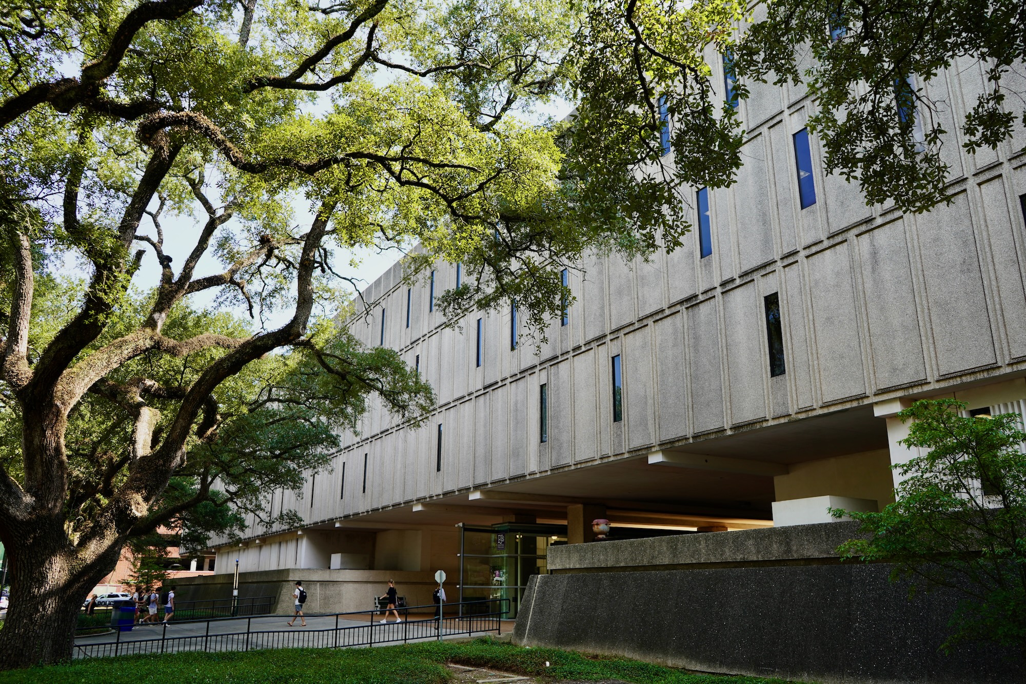 Photograph of a large concrete building framed by leafy trees.
