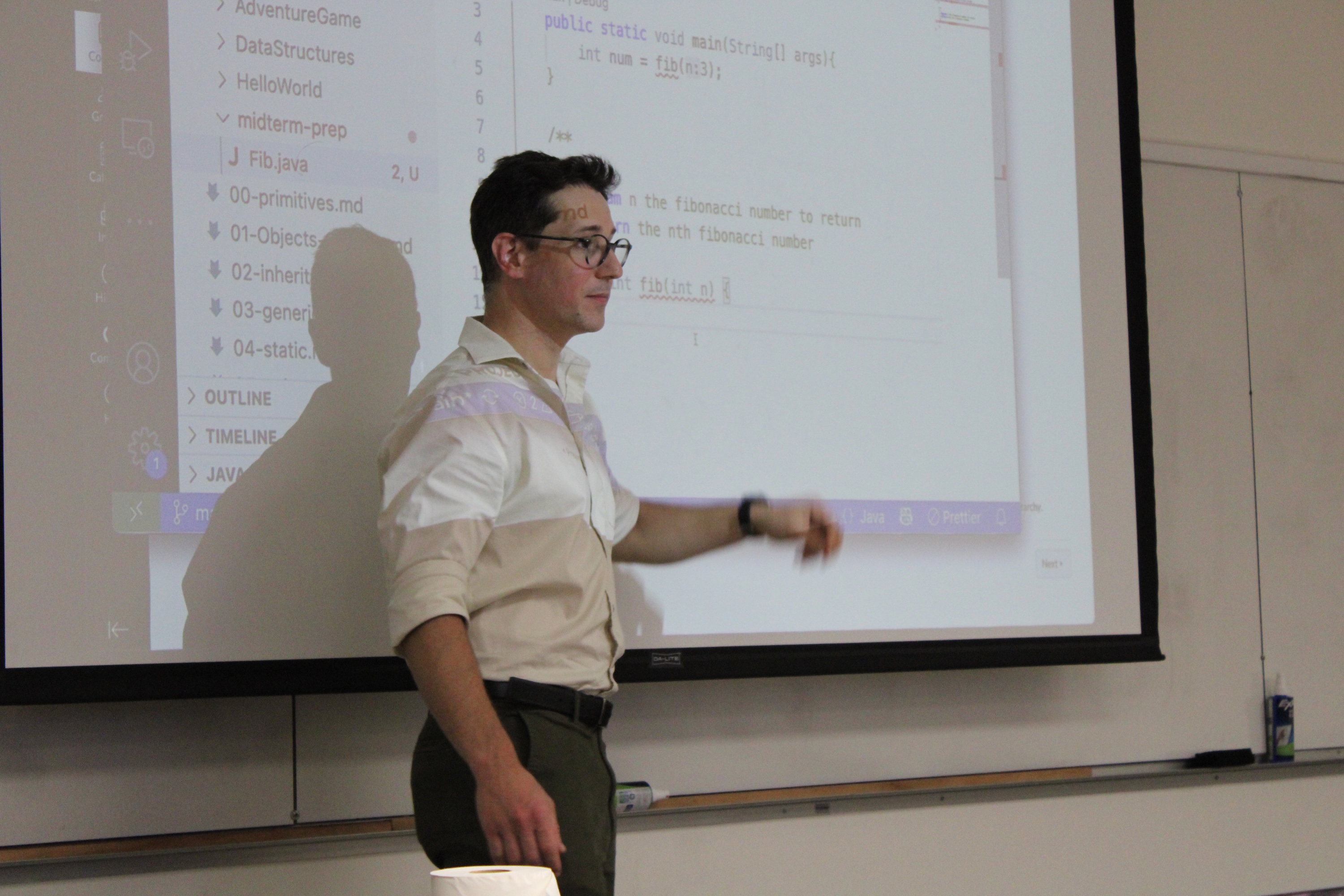 Man in white button down standing in front of projector screen
