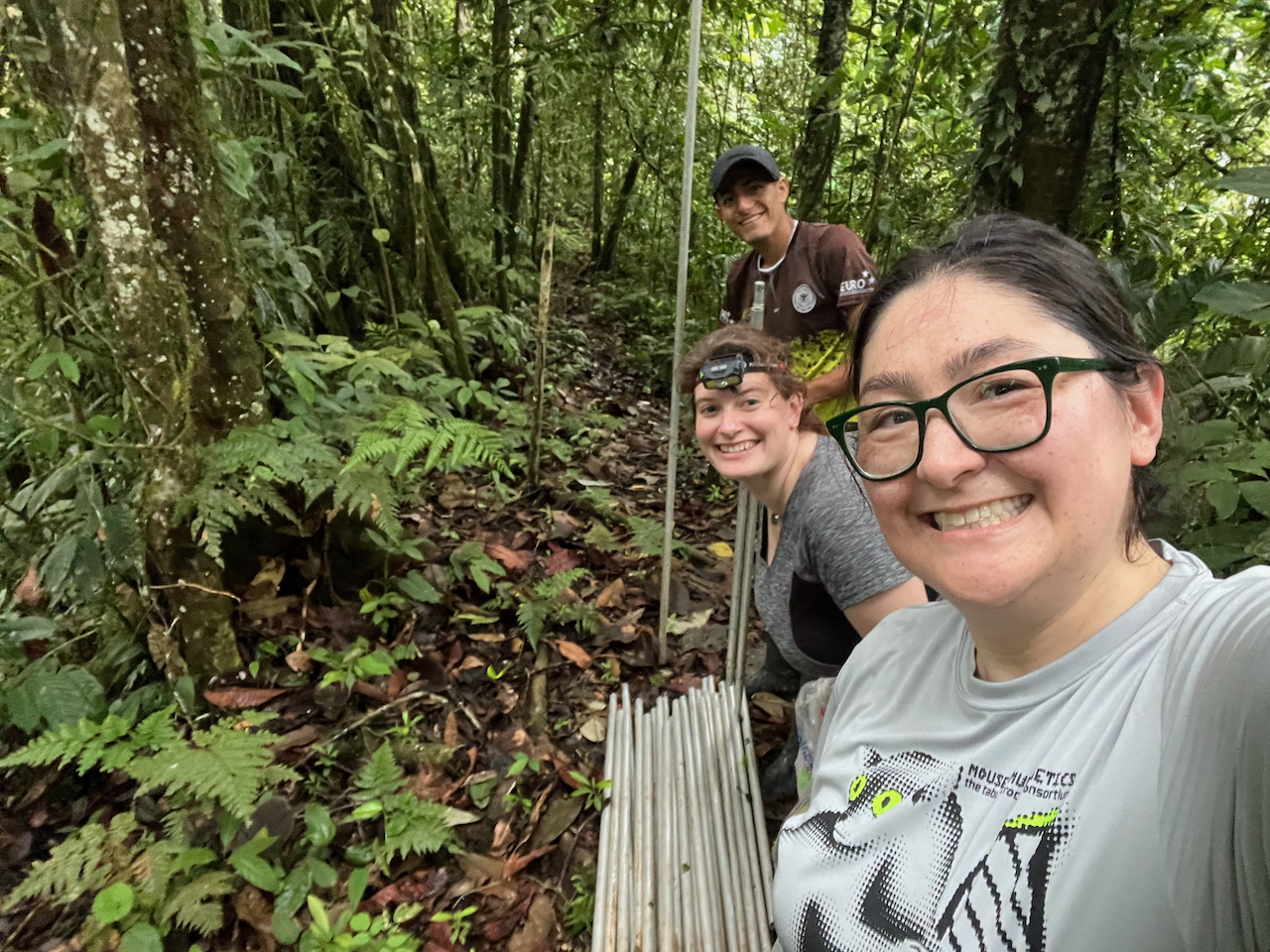 Photo of three smiling hikers on a lush green forest trail.