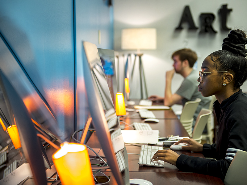 Photograph of students working at computers in a modern lab.