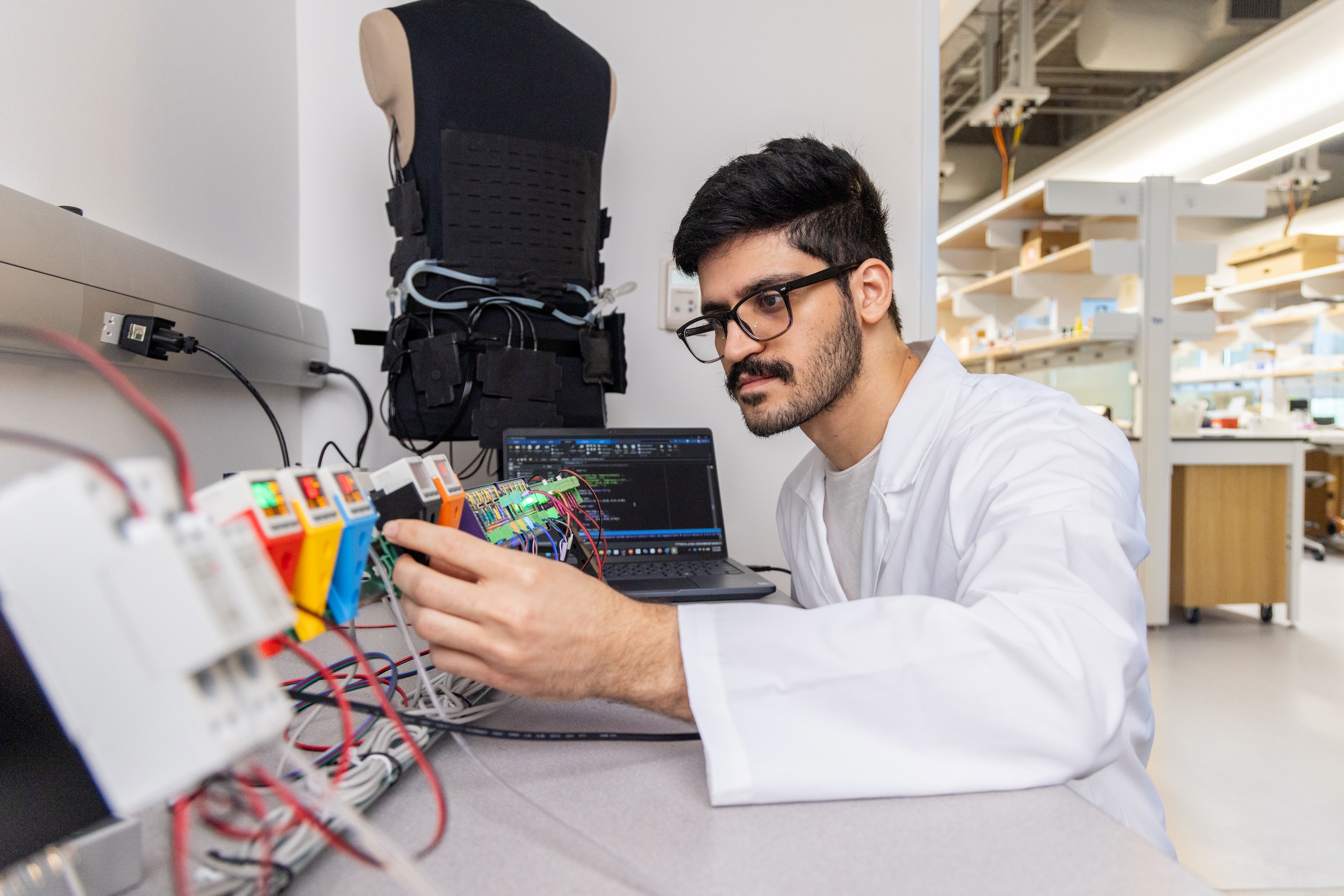 Photograph of a researcher examining a circuit in a bright laboratory.
