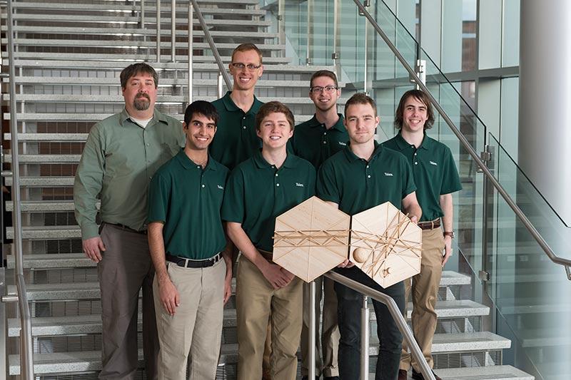 Picture of seven men in green polos standing on stairs smiling