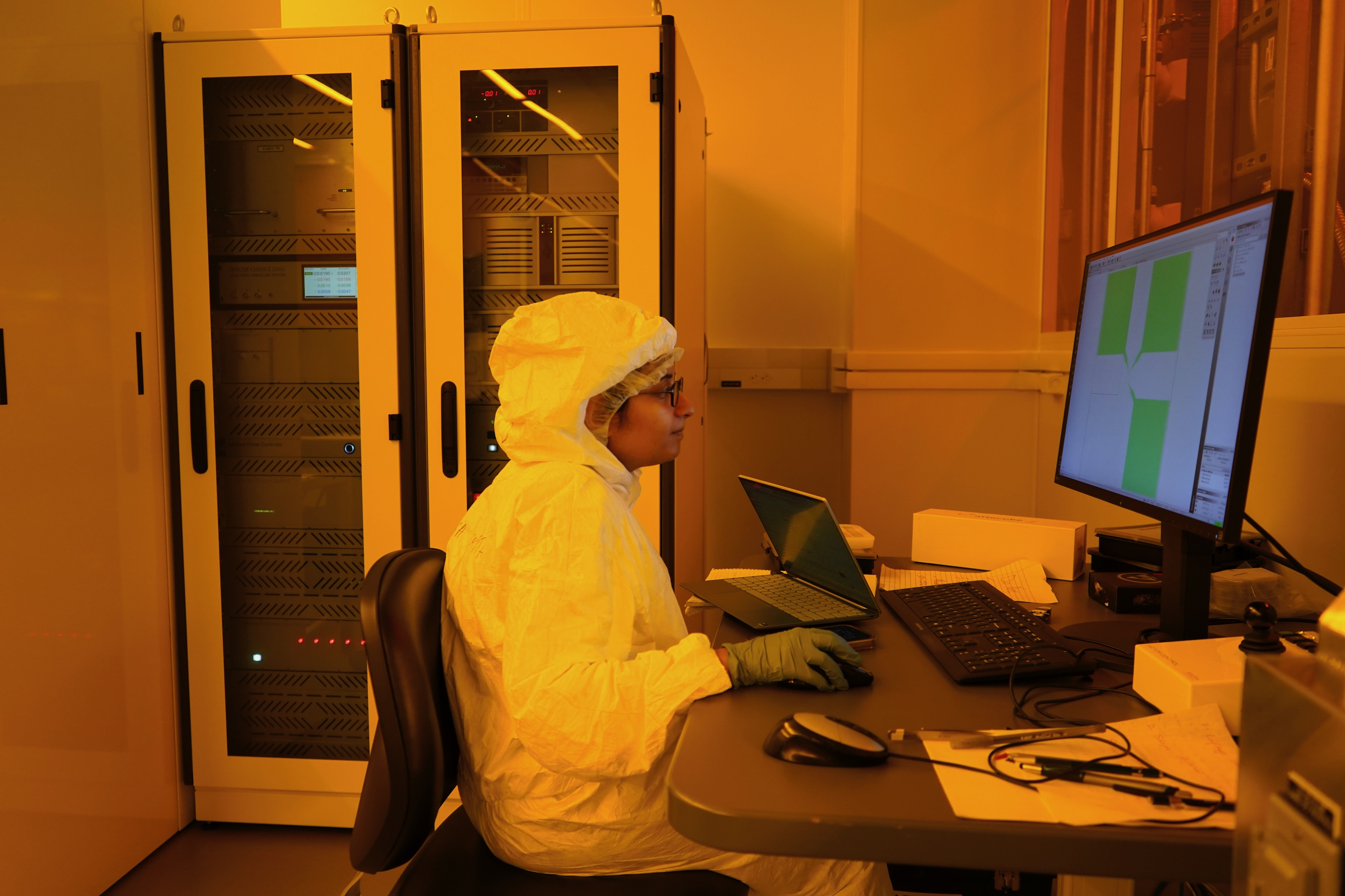 Photograph of a researcher in a cleanroom using a computer.