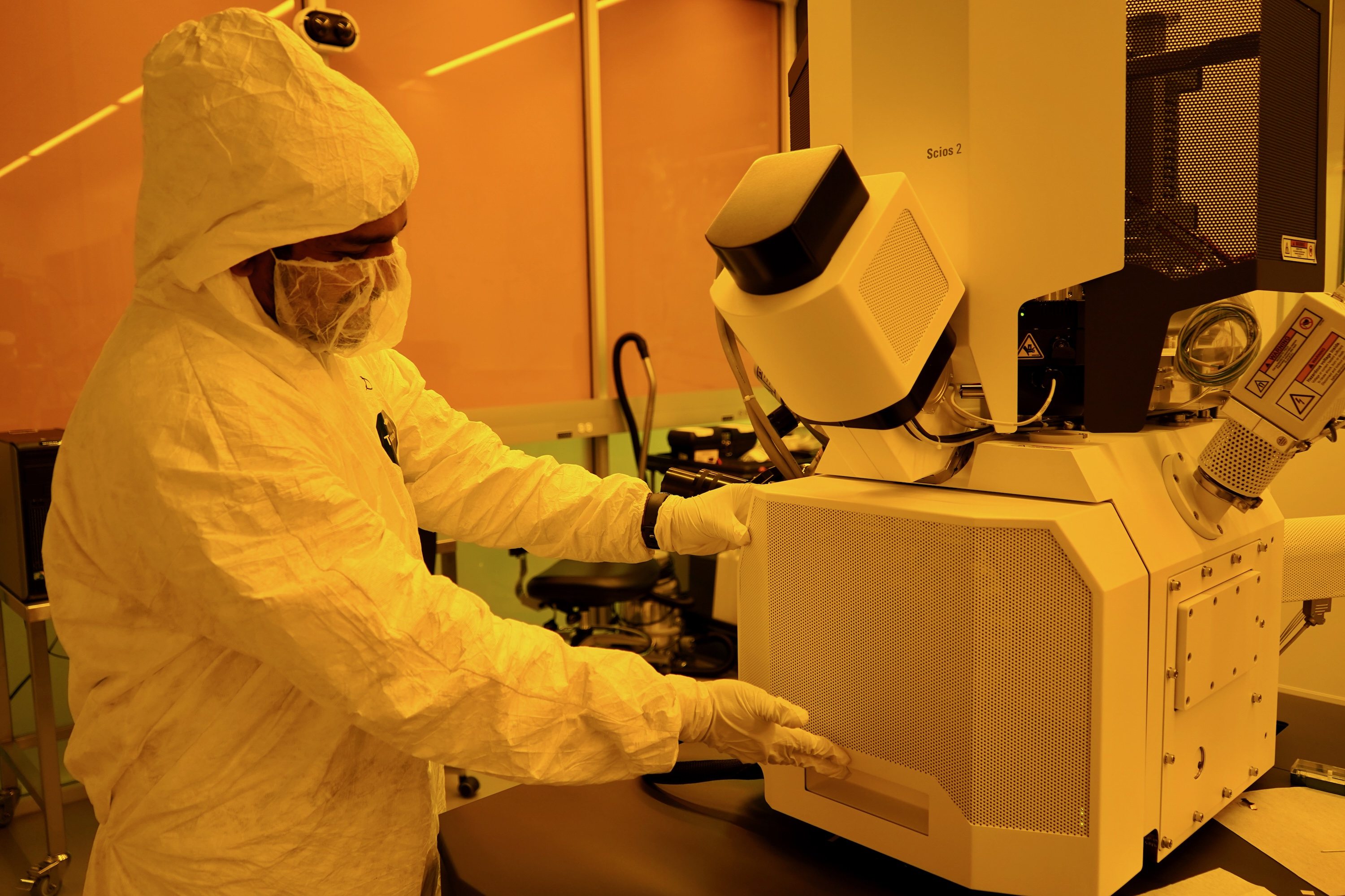Photograph of a researcher in a cleanroom using a large piece of scientific equipment.