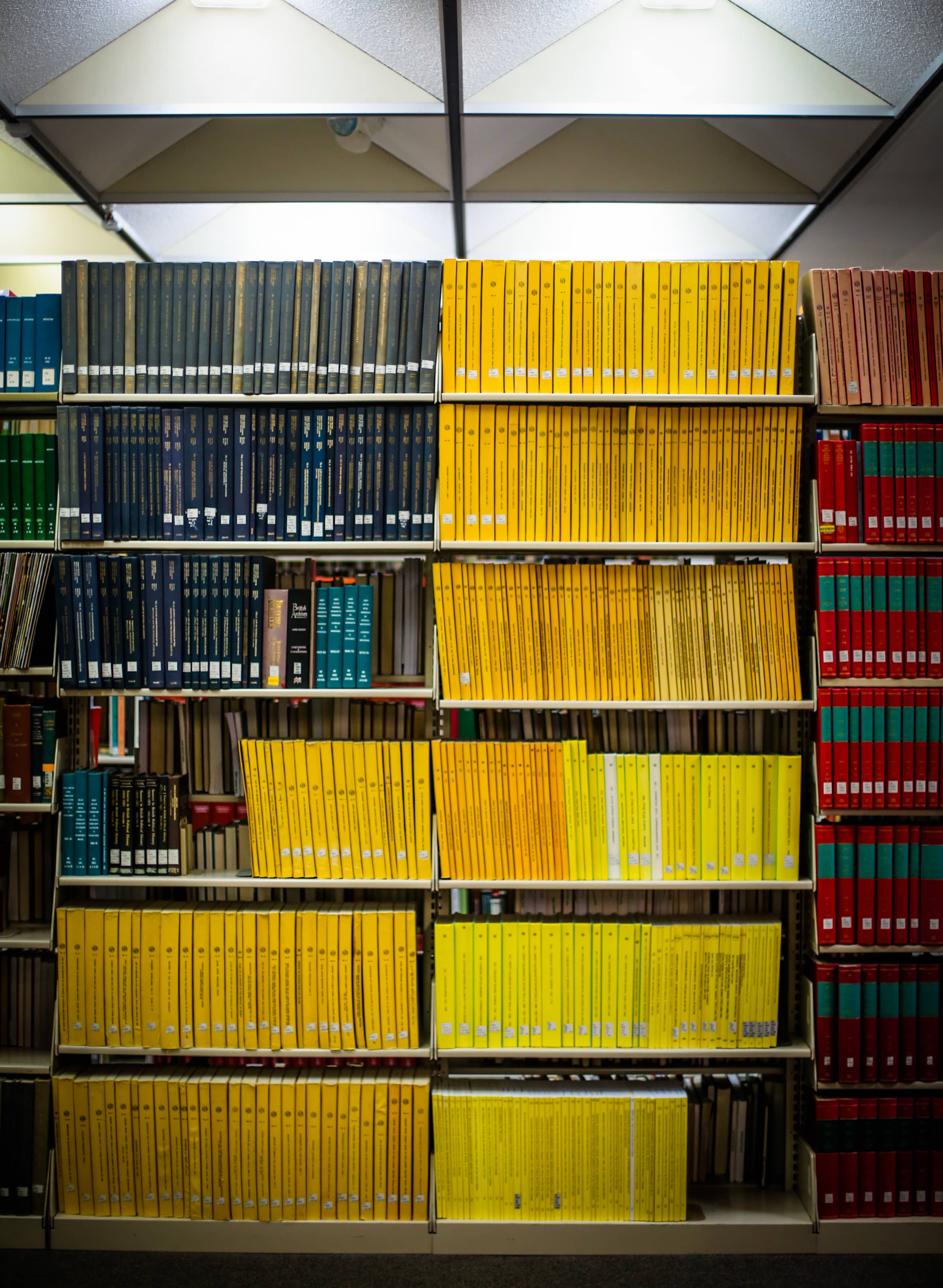 A photograph of a tall bookshelf packed with colorful yellow, blue, and red books.