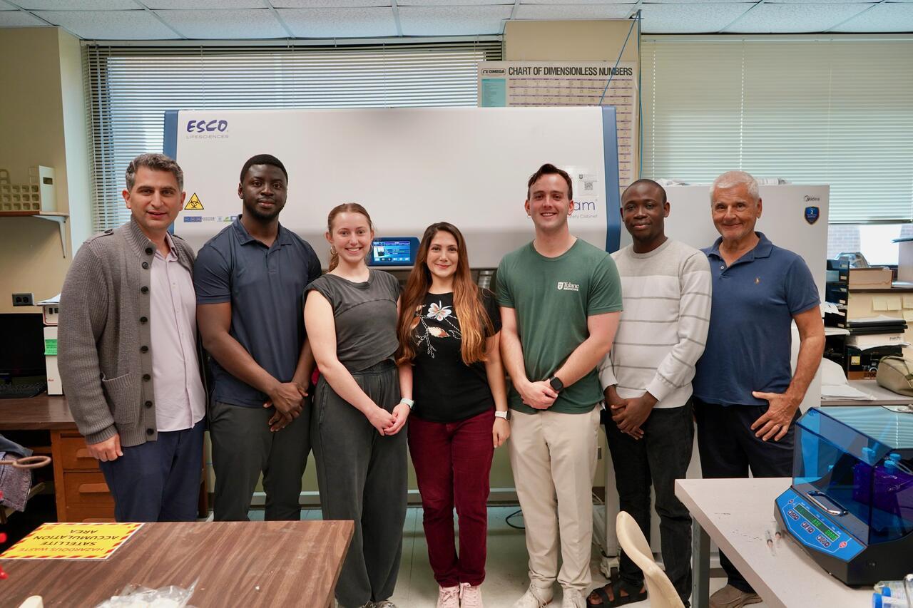 A group of seven diverse colleagues stand smiling in a laboratory.
