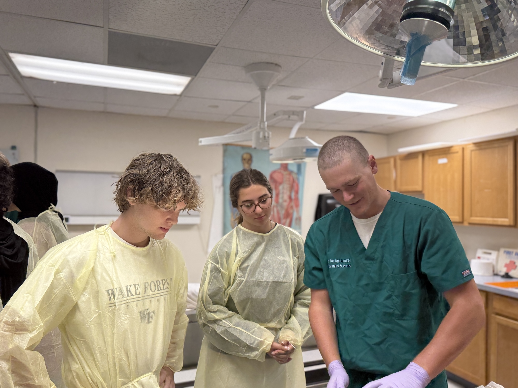 Photo of a male medical professional demonstrating a procedure to two students.
