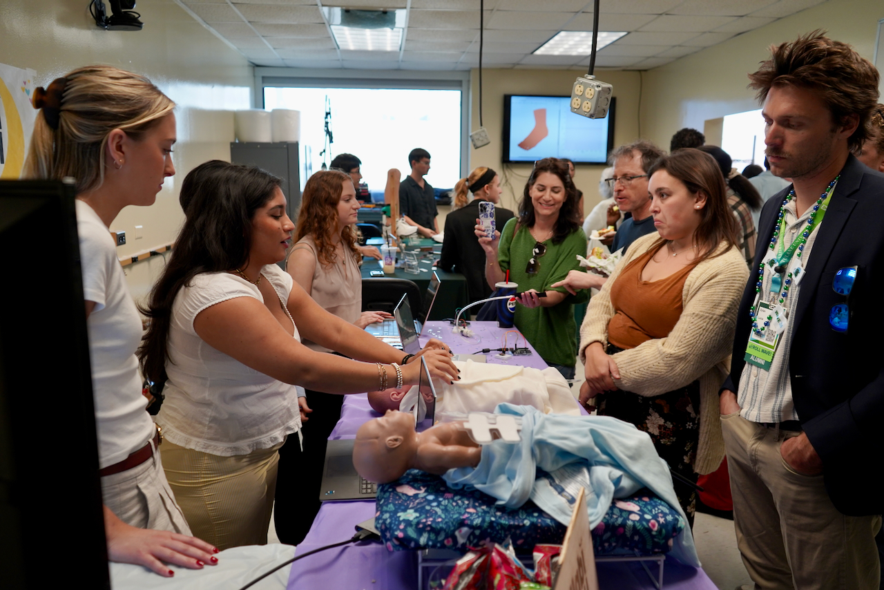 Photograph of people gathered around medical training manikins in a classroom setting.