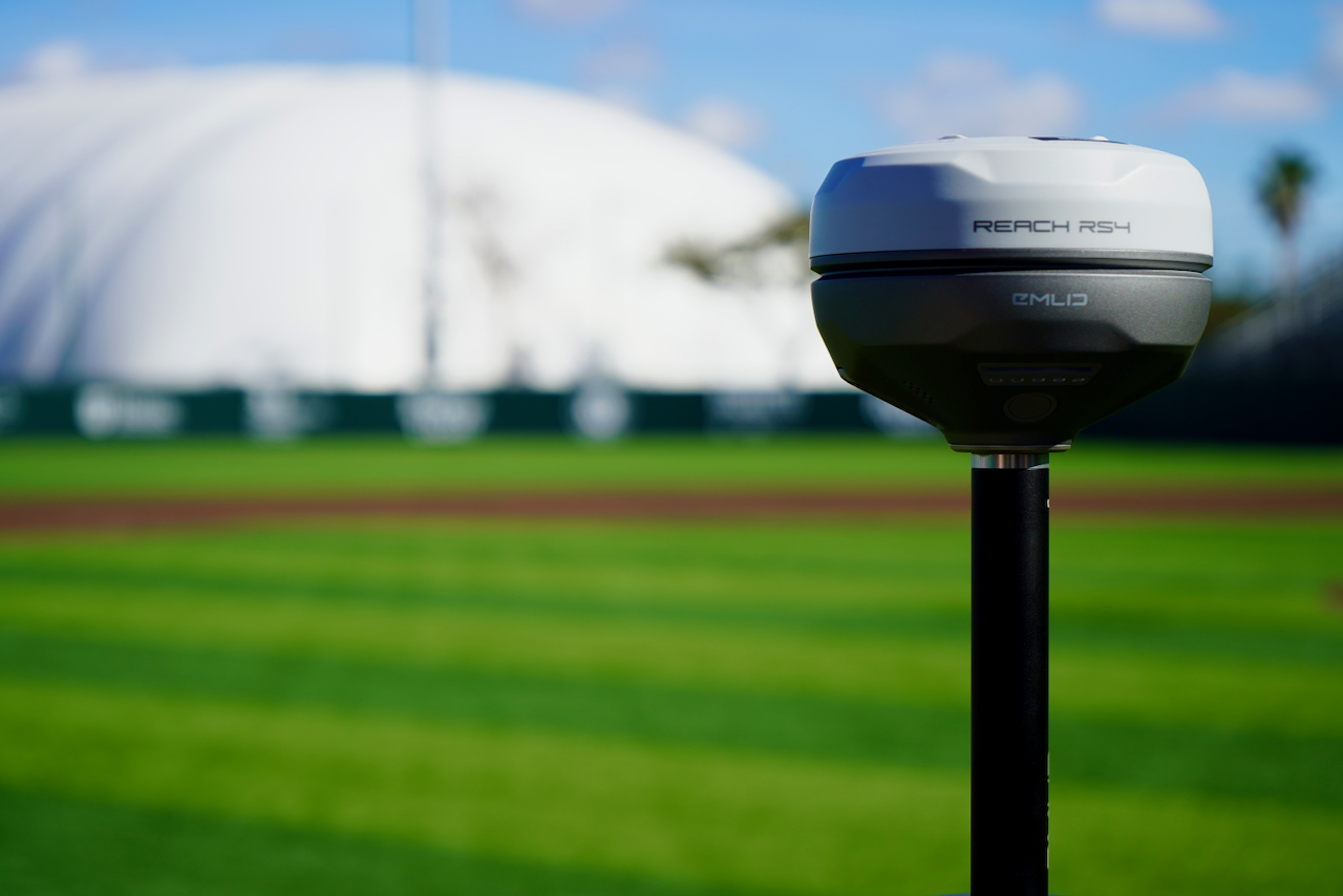 Photograph of an RTK GNSS receiver on a pole on a baseball field.