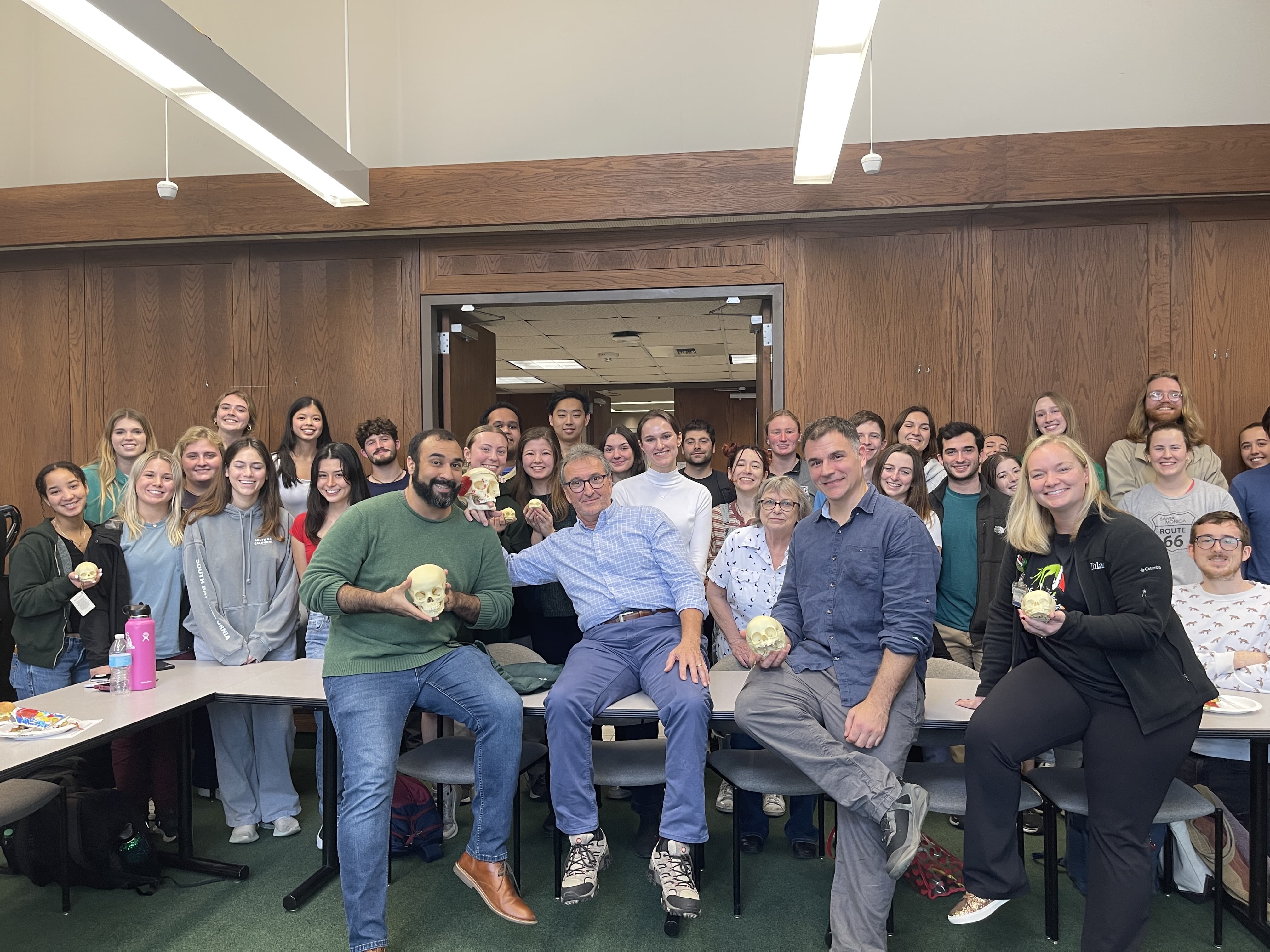 A group of people holding squashes in a wood-paneled room.