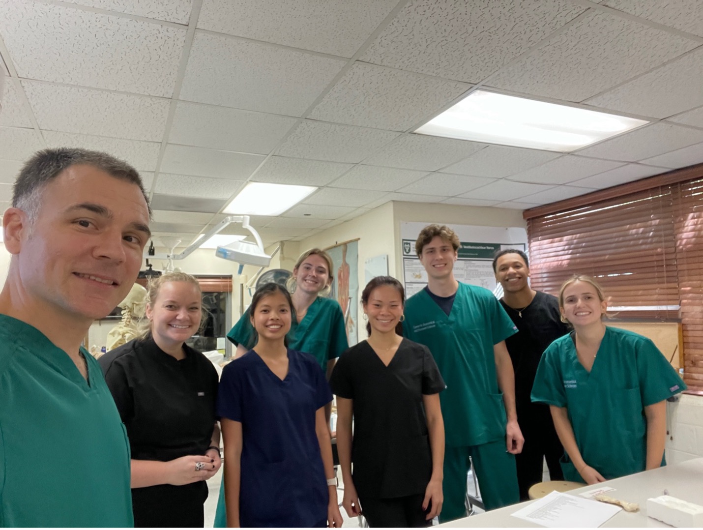 Photograph of smiling healthcare workers in scrubs in a clinic.