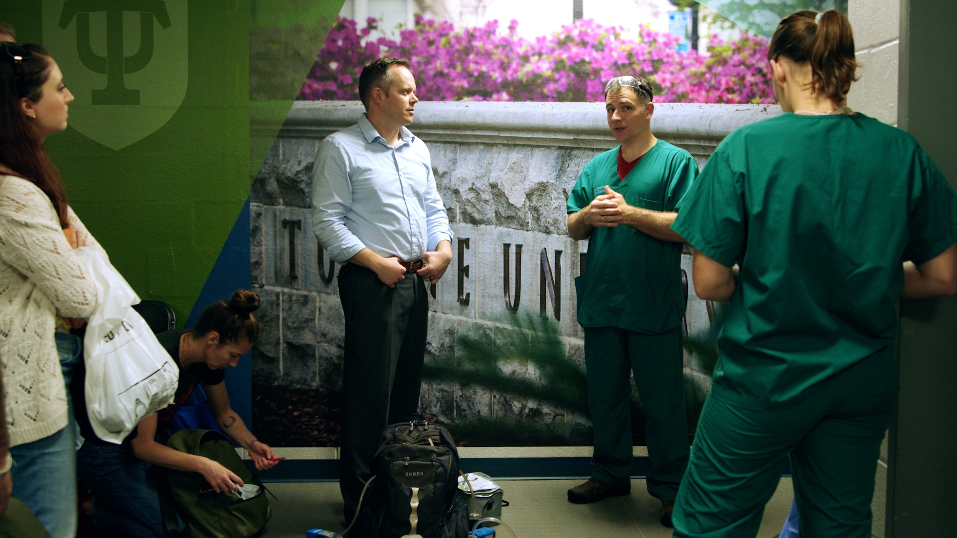 Photograph of a man and a doctor in scrubs talking in a hallway.