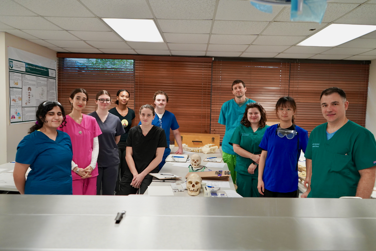 Photograph of a diverse group of medical students in scrubs inside a classroom.