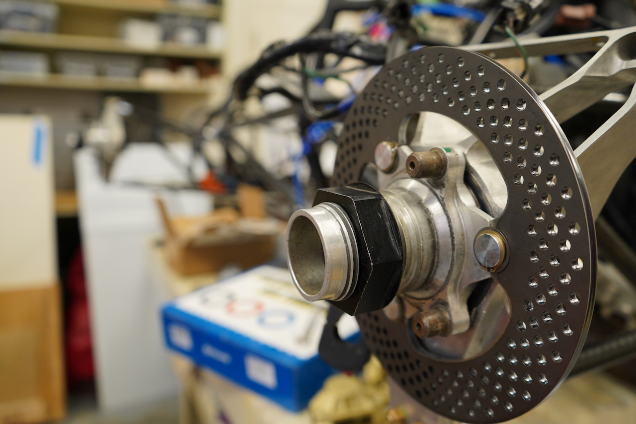 A close-up photograph of a motorcycle's perforated disc brake assembly.