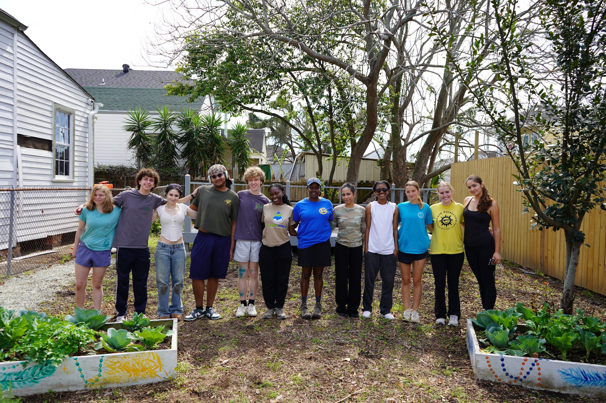 Photograph of diverse volunteers posing in a community garden between garden beds.