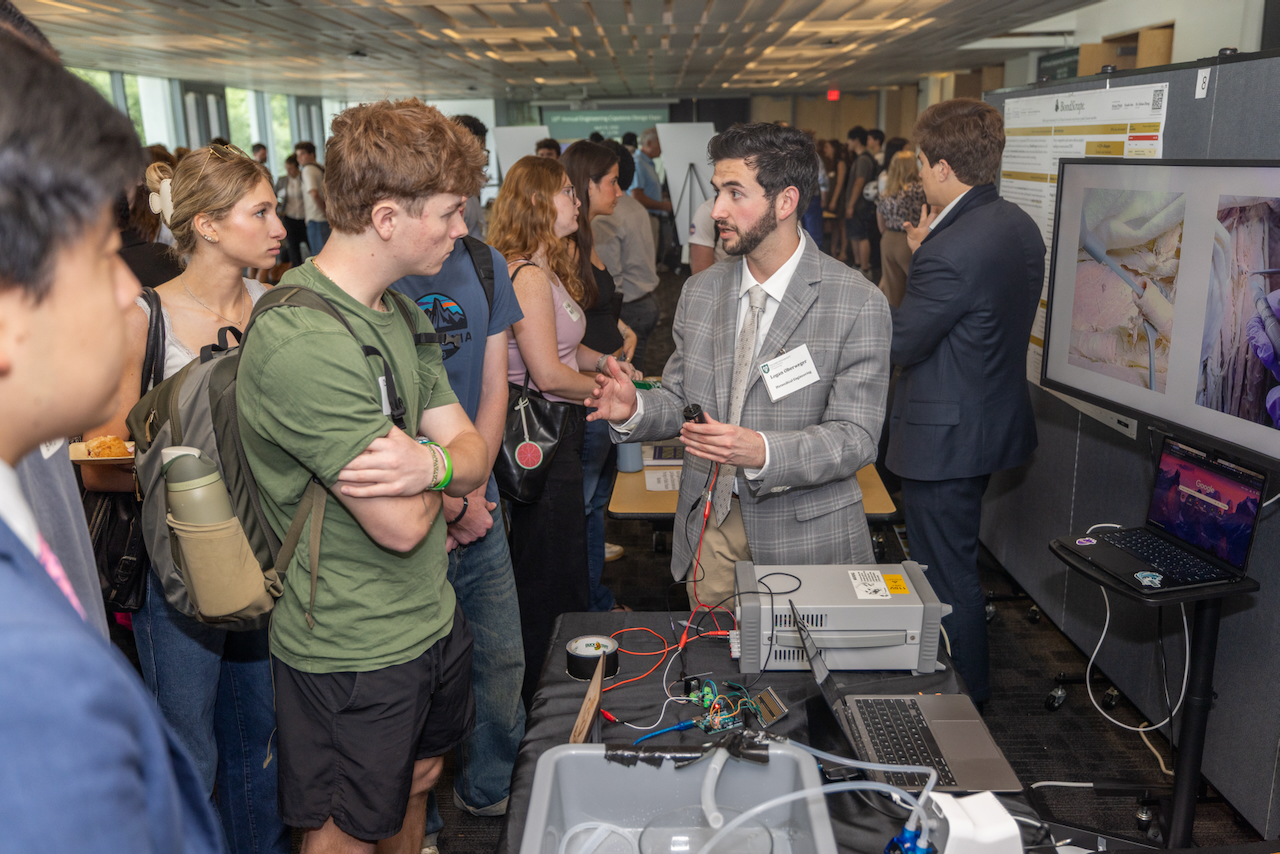 Photograph of a man in a suit presenting his project to students.