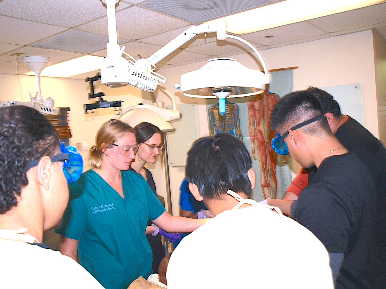 Photograph of medical students surrounding a patient in a clinic.