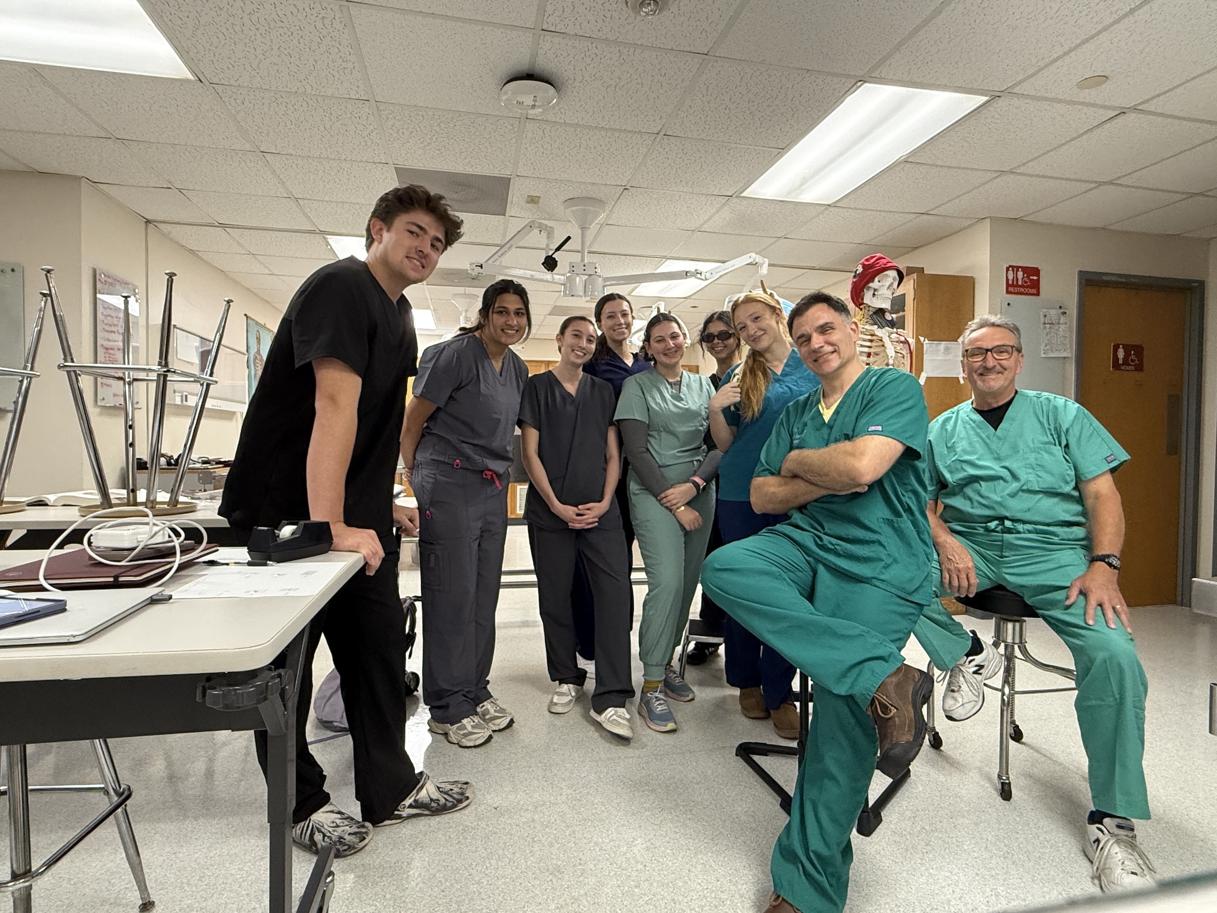Photograph of a group of diverse healthcare workers posing together in a brightly lit medical room.