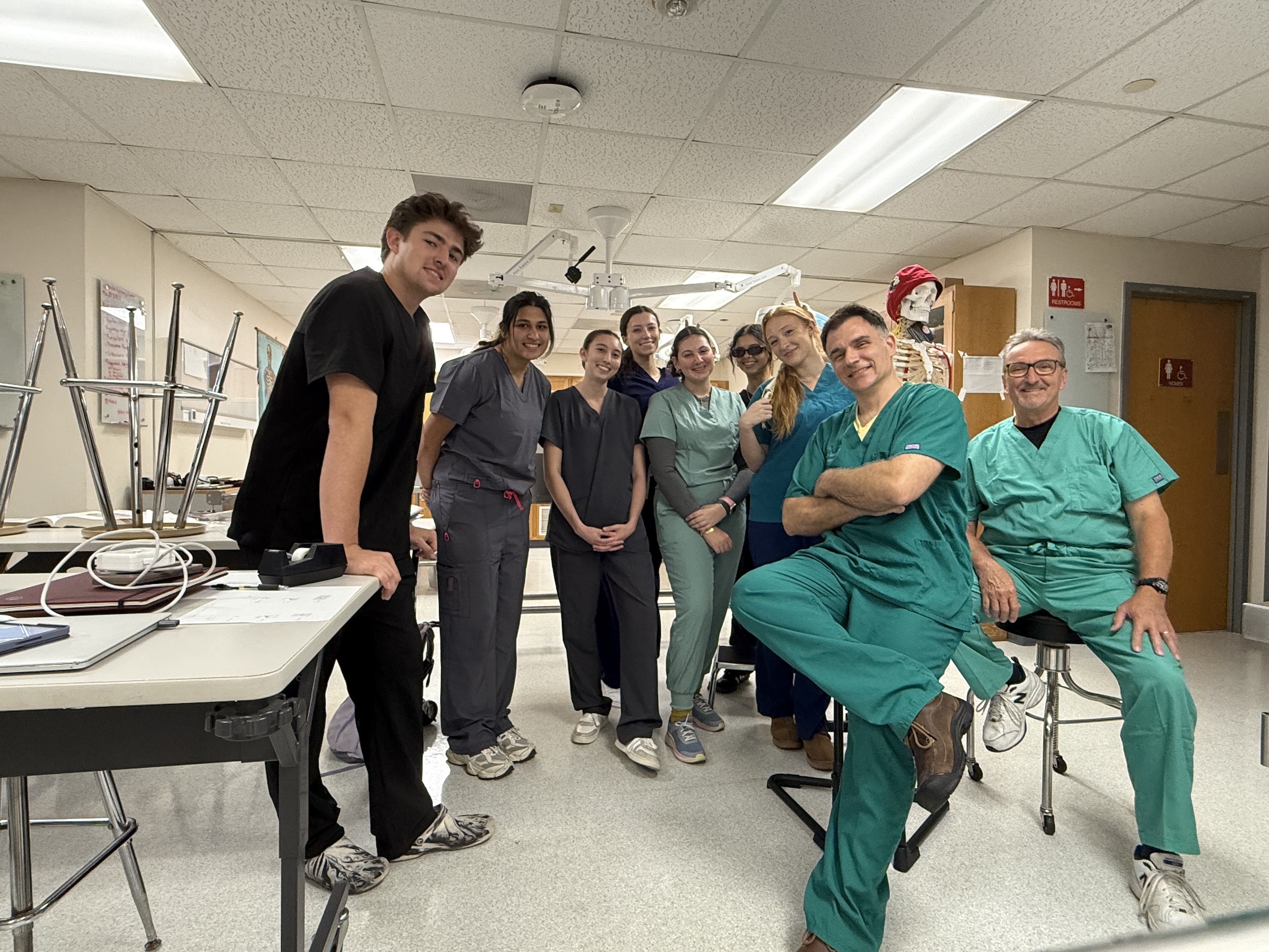 Photograph of eight medical professionals smiling in a classroom.
