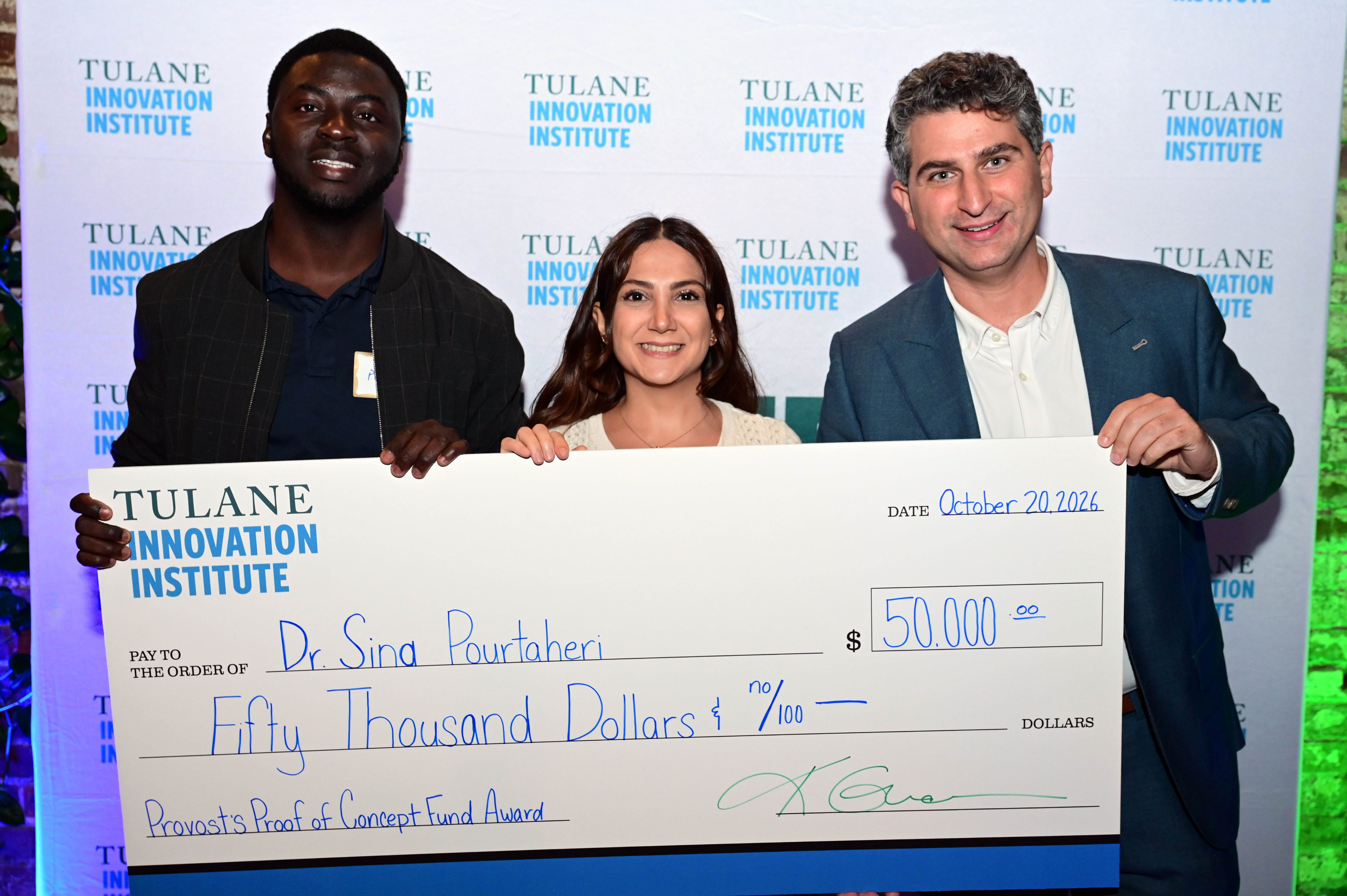 Photograph of three people smiling while holding a large novelty check for 50,000 dollars.