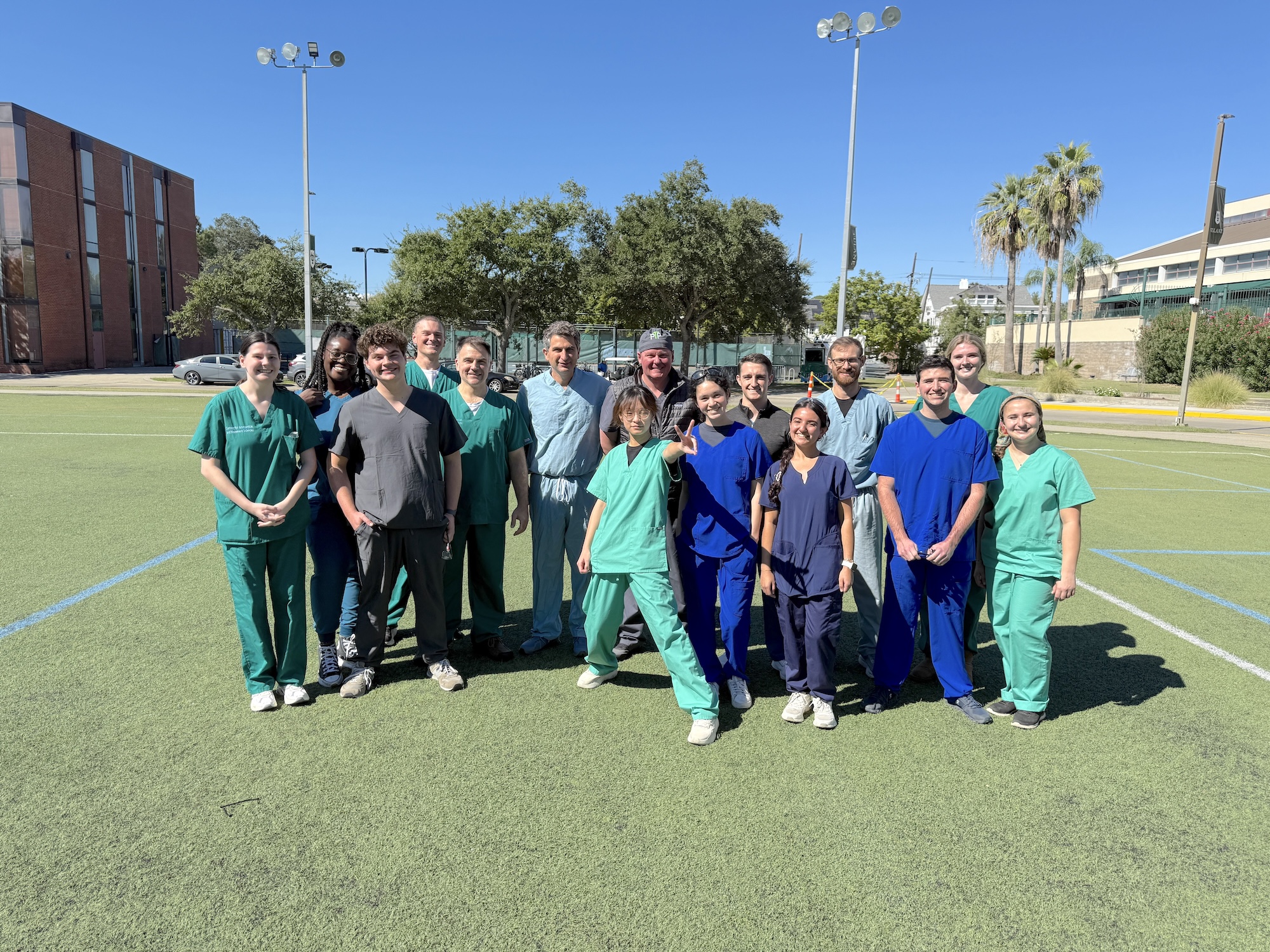 A group of people in scrubs on a sunny green field.
