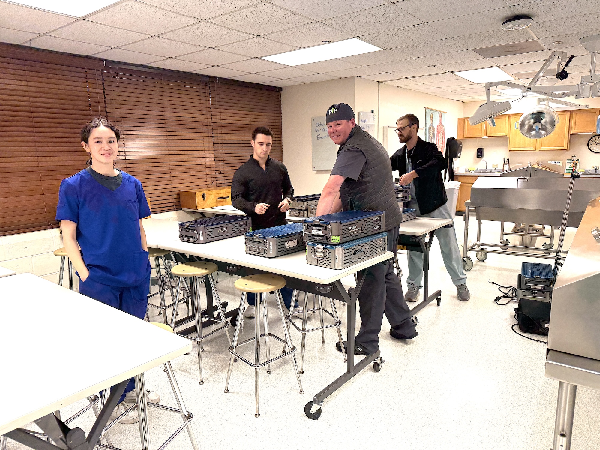 Photograph of four people in a lab classroom with computers on desks.