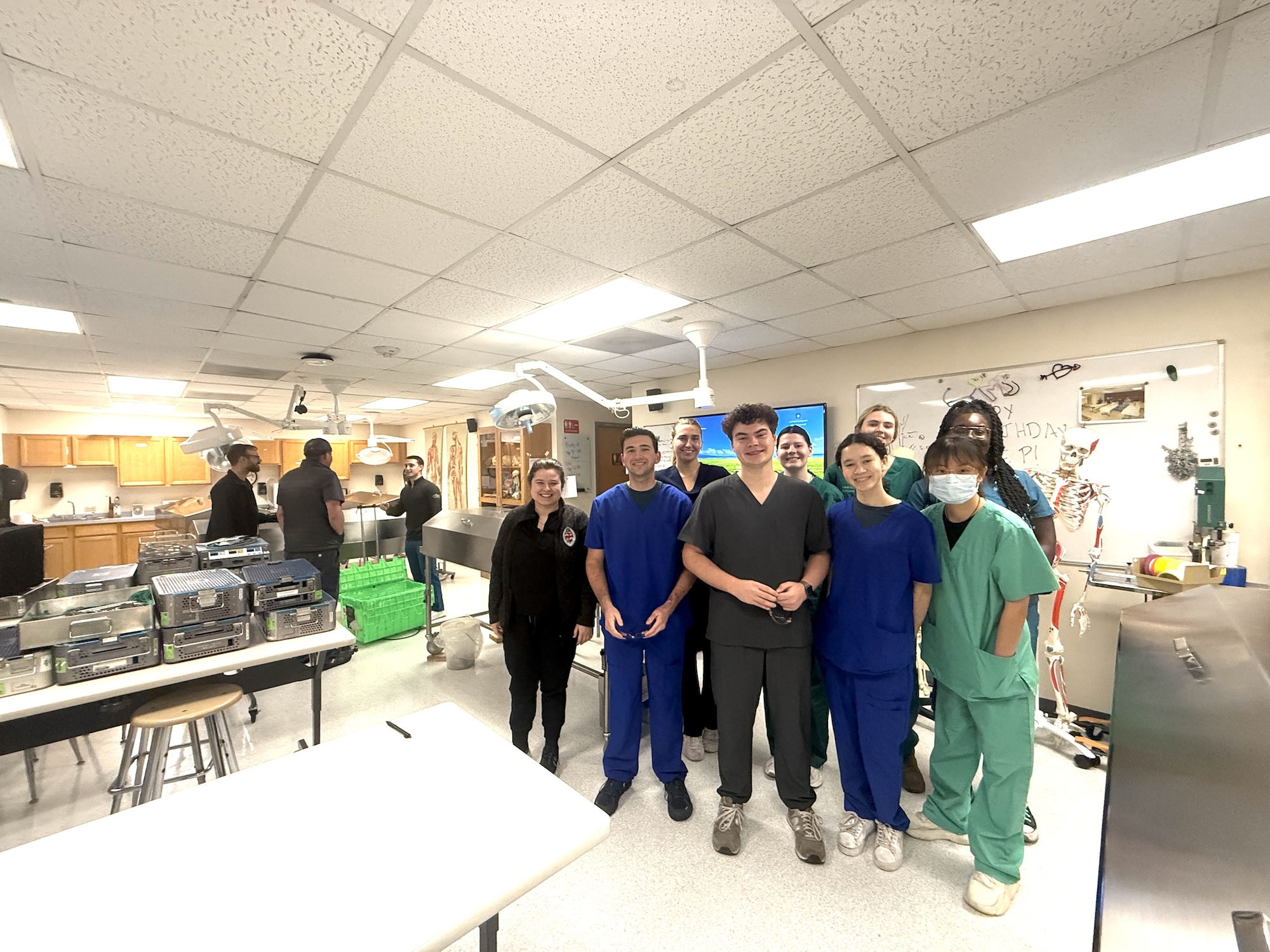 A wide-angle photo of a group of medical staff standing in a brightly lit training room.