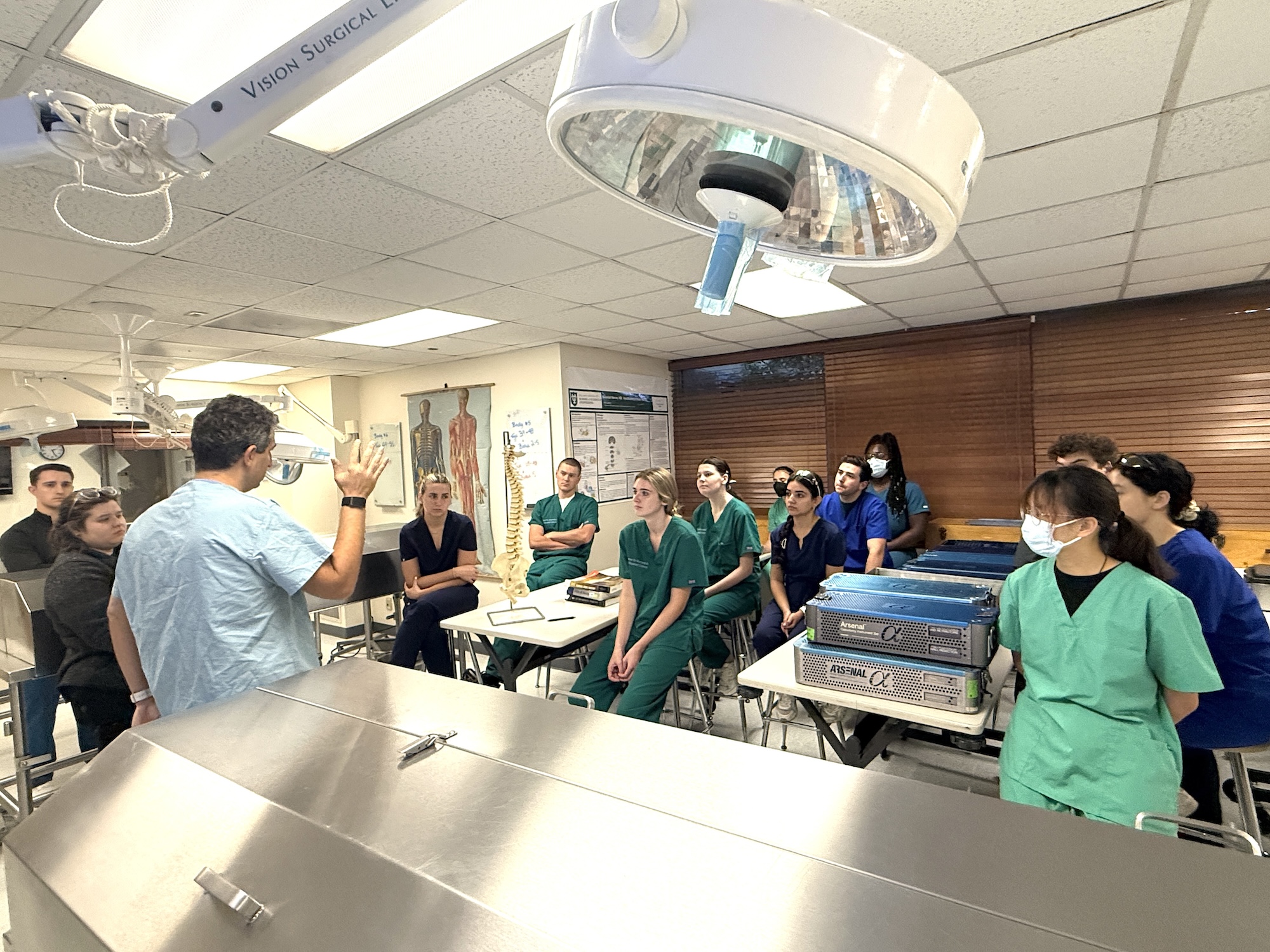 Photograph of a lecturer speaking to a group of students in a lab.