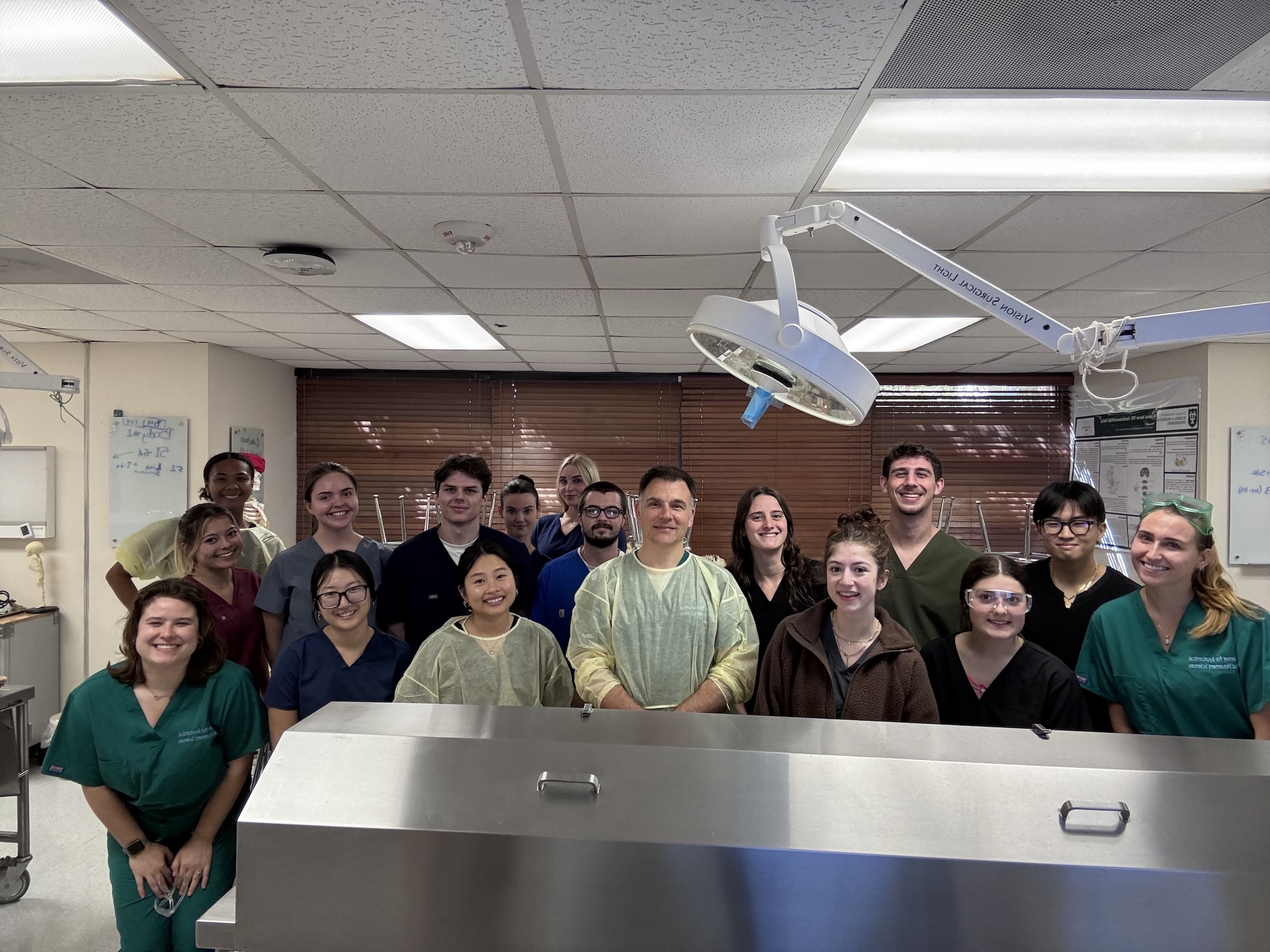 A group of students in scrubs posing together in a medical lab setting.
