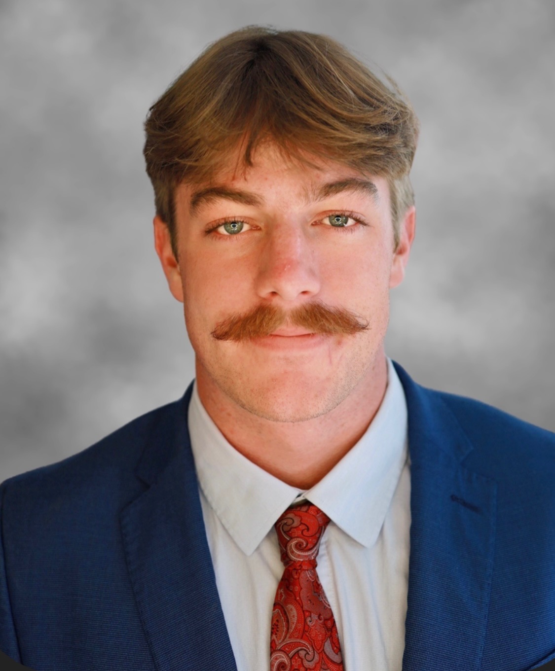 Portrait of a young man with a mustache in a suit.