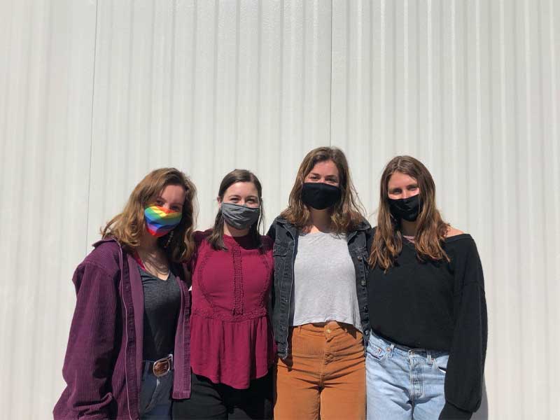 Four Tulane seniors posing together with masks on.