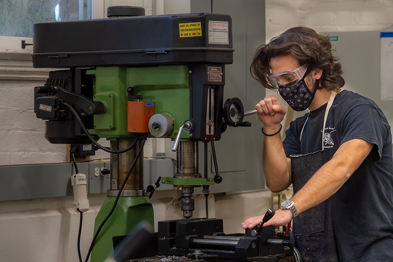 Undergraduate student Will Kadison works with a wood machine to create a high chair.