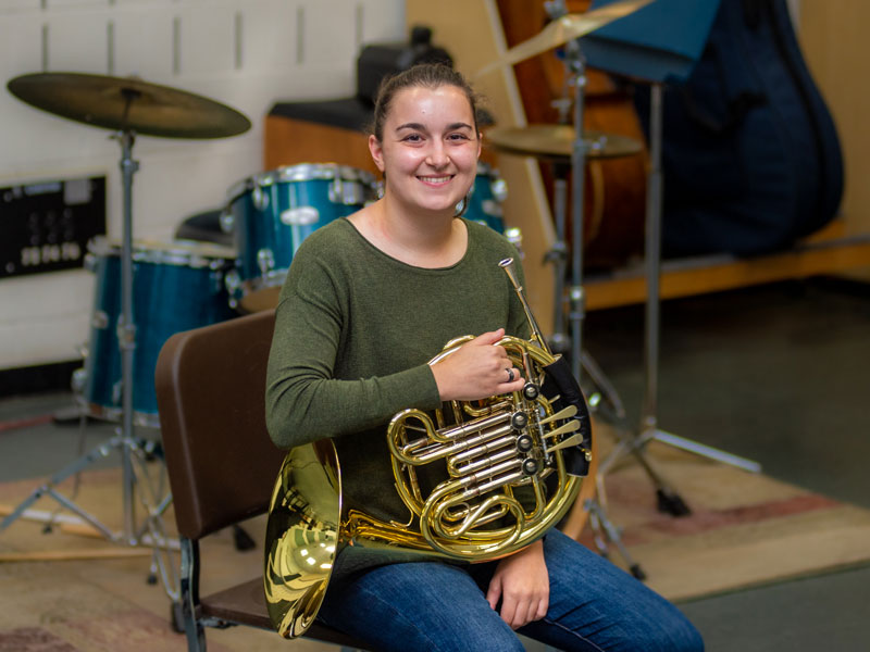 Jacie Pujol sitting with her french horn