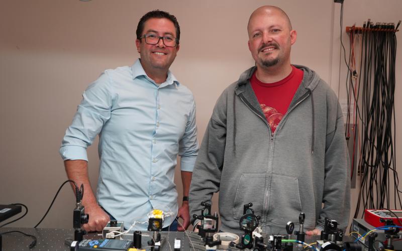 Two men standing behind a table with scientific equipment.