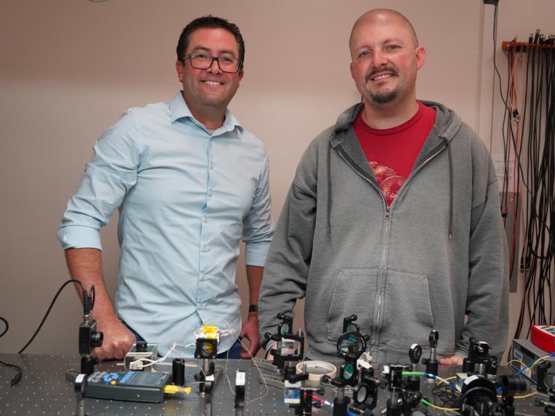Two men standing behind a table with scientific equipment.