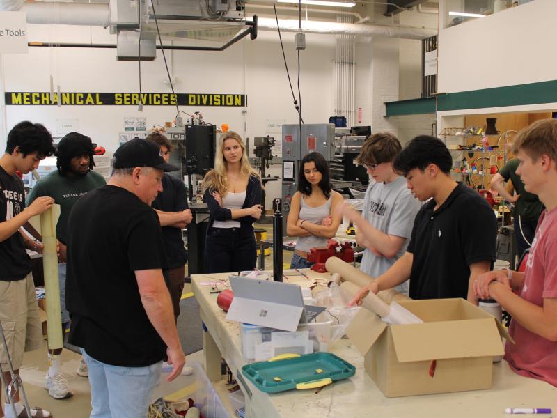 Group of students and an instructor working on a project in a workshop.