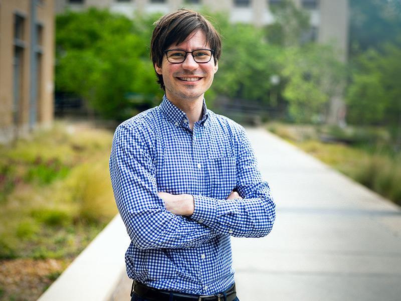 Man with glasses in a blue checkered shirt with arms crossed.
