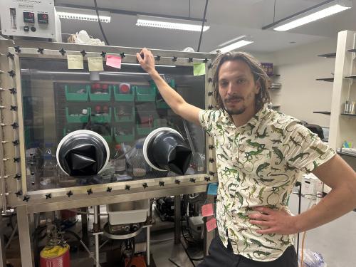 Alex McSkimming standing next to a glove box in his lab