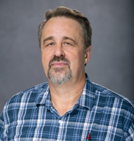 Portrait of a man with a goatee, wearing a blue plaid shirt.