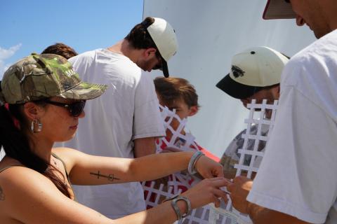 Young adults in casual clothing working on a project outdoors on a sunny day.